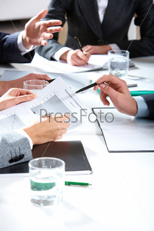 Photo of business people hands holding papers and pens over workplace
