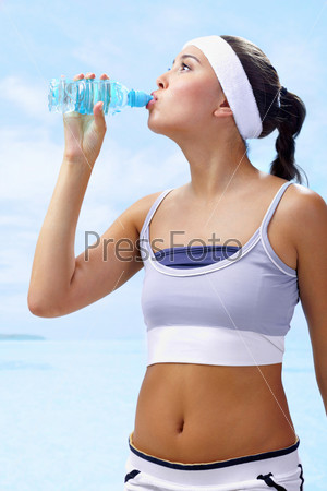 Portrait of lovely girl holding bottle of water in hand and drinking, stock photo