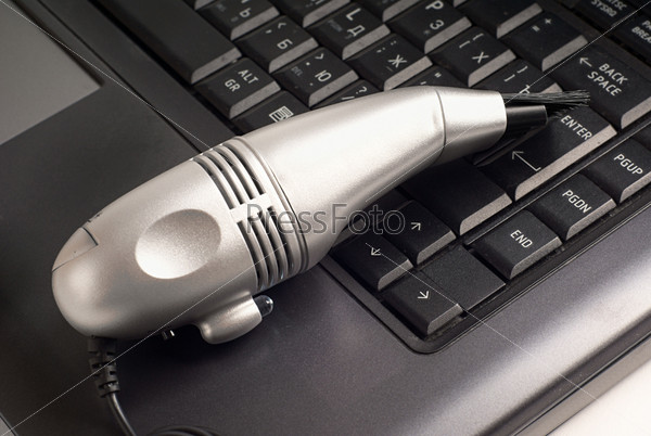 Small silver vacuum cleaner on laptop keyboard