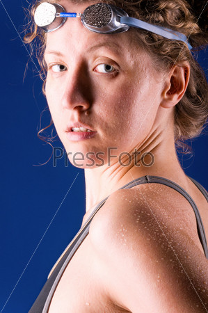 sexy woman swimmer is looking at camera, on blue background
