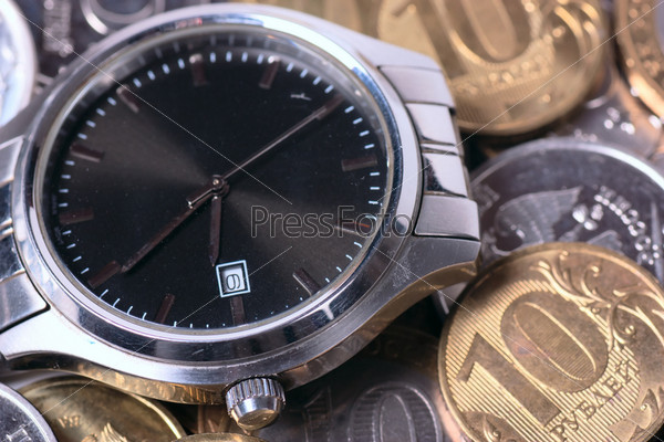 Wrist watch over coins. Time is money concept.