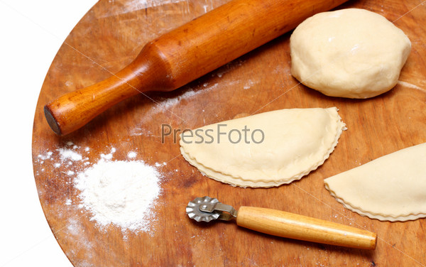 rolling-pin with patty and pastry on wooden board