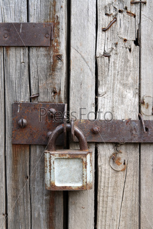 old rusty padlock on wooden door of old shed
