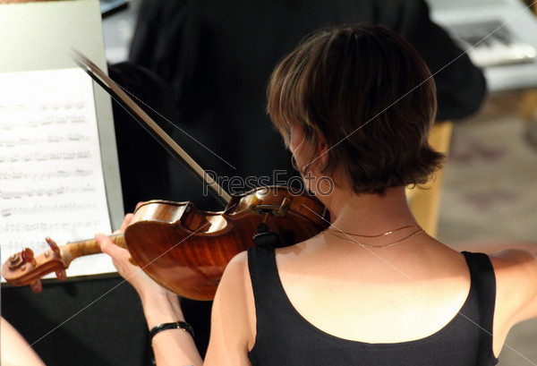 Woman playing on violin in orchestra
