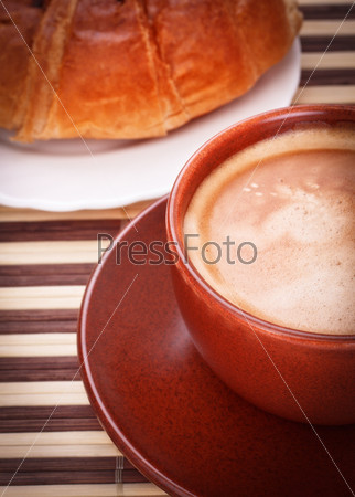 fresh coffee cup and croissant on bamboo napkin