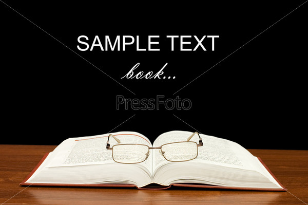 Eyeglasses on books on a wooden table