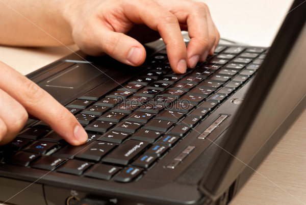 Male hands typing on a laptop keyboard. Focus on keyboard, stock photo