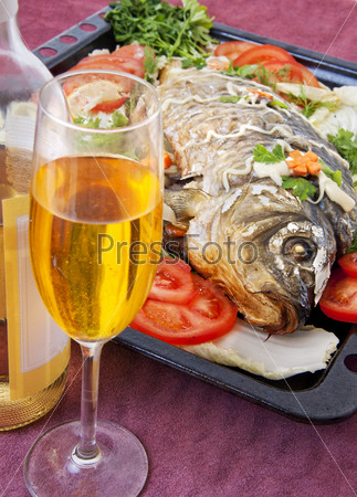 Fried fish with vegetables. And white wine in glass