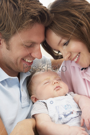 Счастливые молодые родители и спящий ребенок