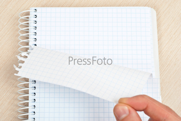 Hand tearing one paper page from notepad on desk