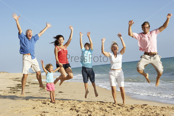 Portrait Of Three Generation Family On Beach Holiday Jumping In Air