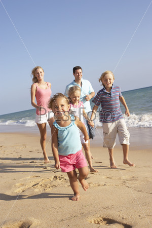 Семья из пяти человек бежит по морскому пляжу