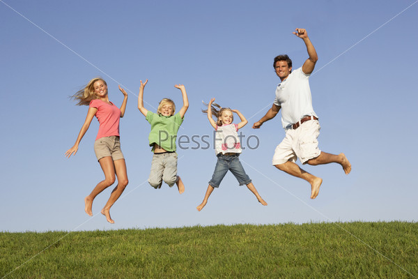 Young couple with children jump in a field