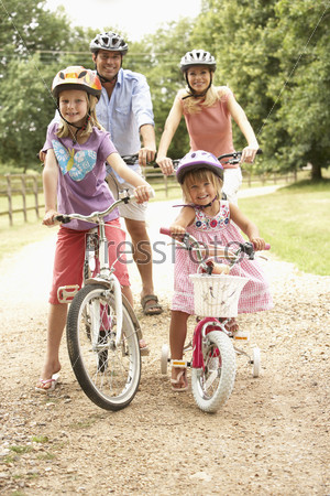 Молодая семья катается на велосипедах в парке