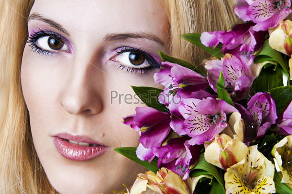Fashion portrait of seductive female face with perfect skin. Young woman with bright pink spring makeup and bunch of exotic  flowers