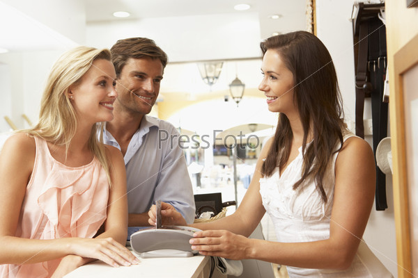 Улыбающийся продавец-консультант с покупателями в магазине одежды