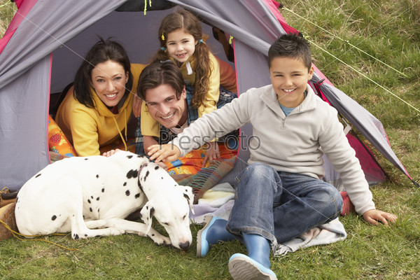 Young Family With Dog Relaxing Inside Tent On Camping Holiday, stock photo