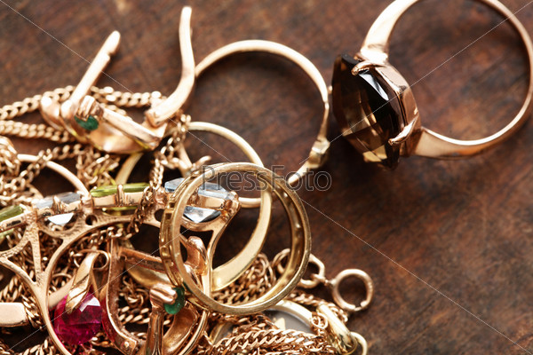 Closeup of pile of gold jewelry on wooden surface