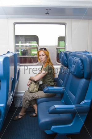 Interior of a passenger train with young woman, sitting into the railway car, stock photo