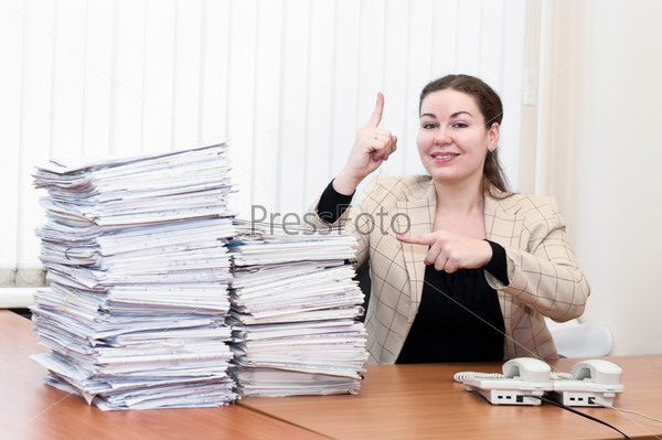Young caucasian woman near pile from project drawings blueprints showing on it