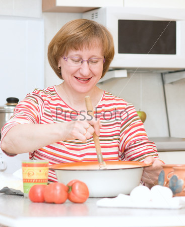 Joyful elderly woman cooking in the kitchen at home