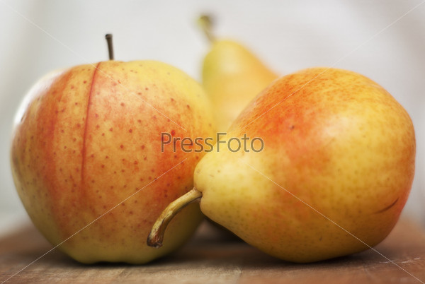 Спелые груши и яблоко крупным планом на столе