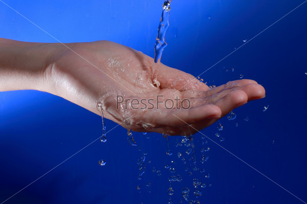 A studio shot of a water stream poured on the woman\'s hand