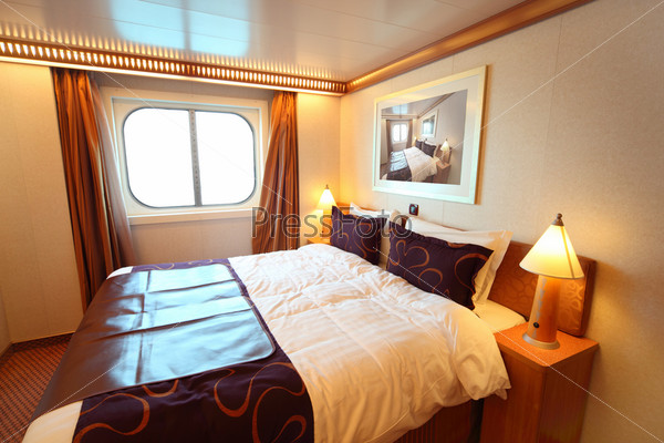 Ship cabin with big double bed and window summer day