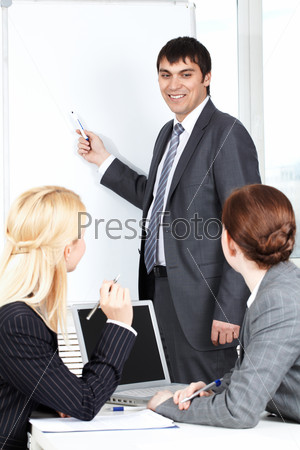 A business man showing something on a whiteboard to his colleagues
