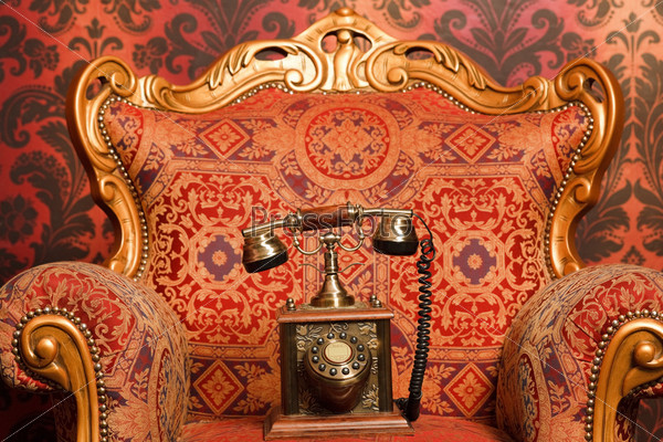 old phone is a red chair with gold accents, red vintage wallpaper. Focus on phone