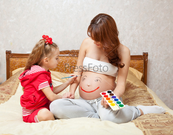 A daughter is painting on her mother`s belly