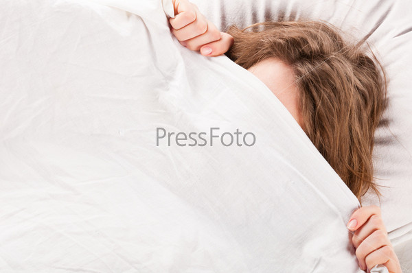 Девушка лежит под одеялом в кровати