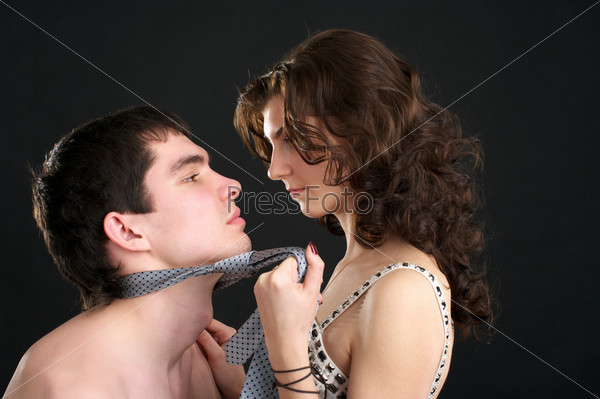 Attractive woman pulls naked man by a necktie
