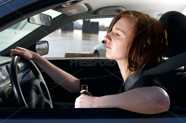 Drunk female driving car with whiskey bottle in her hand