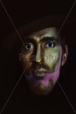 portrait of young attractive man in hat with bronze makeup on her face on black background