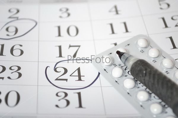 Противозачаточные таблетки, ручка и календарь крупным планом