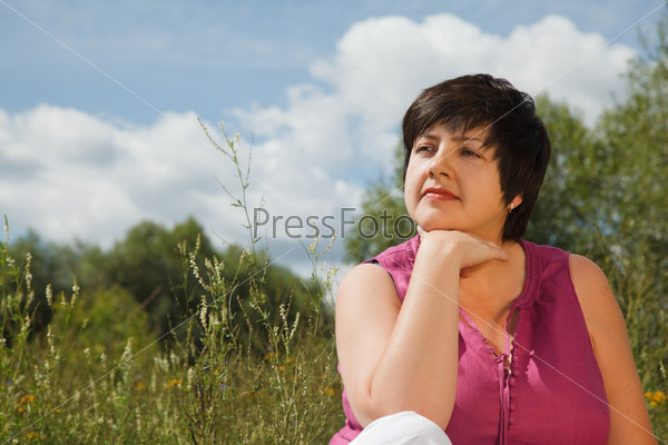 woman in summer day thinks of what that on the nature, looking forward