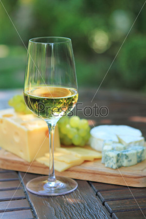 Various sorts of cheese, grapes and one glass of the white wine
