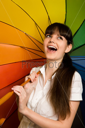 Смеющаяся молодая женщина с разноцветным зонтиком