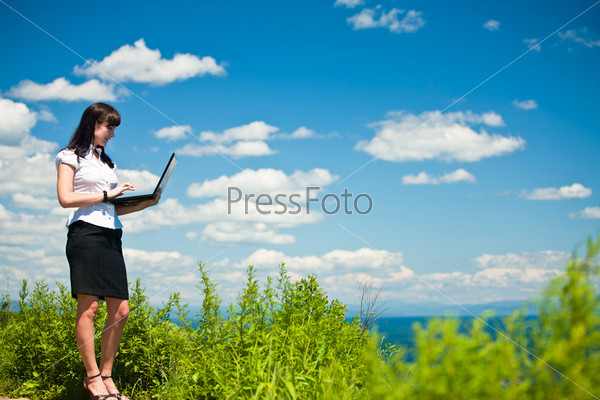 Молодая женщина с ноутбуком на природе