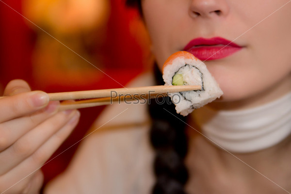 Девушка ест суши