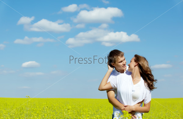 Молодая пара обнимается на зеленом поле