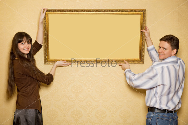 young beautiful woman and smiling man hang up on wall picture in frame
