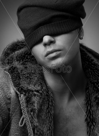 Close-up portrait of handsome young man wearing in a fur jacket and knitted hat (b&w)