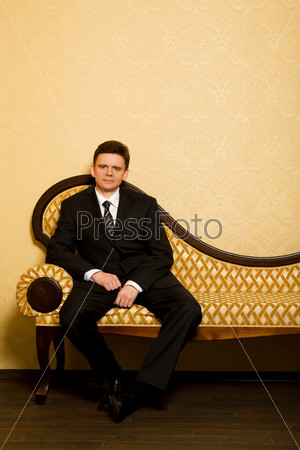 businessman in suit sitting on sofa in room
