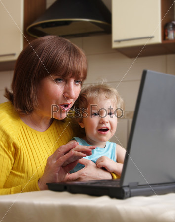 Baby and grandmother with astonishment look in the laptop