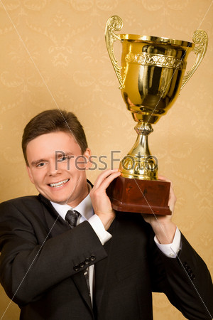 smiling businessman in suit with win cup in hand