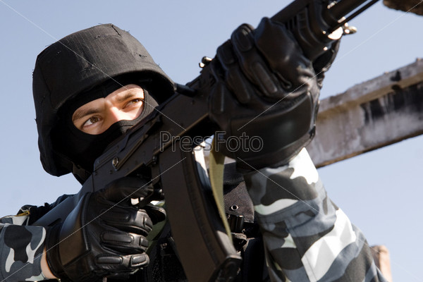 Man in uniform and bulletproof helmet targeting with russian AK-47 rifle
