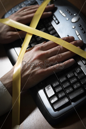 Close-up of a man\'s hand with duct tape typing at a computer keyboard