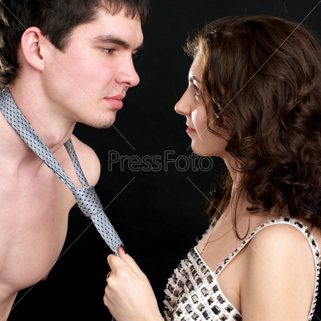Attractive woman pulls naked man by a necktie